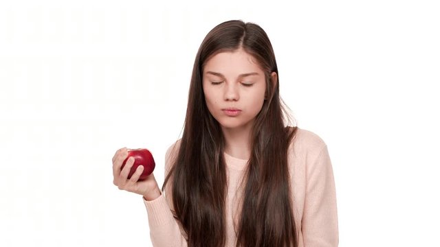 Portrait of nice woman on diet taking pleasure in eating red big juicy apple showing it's tasty with facial expressions over white background. Concept of emotions
