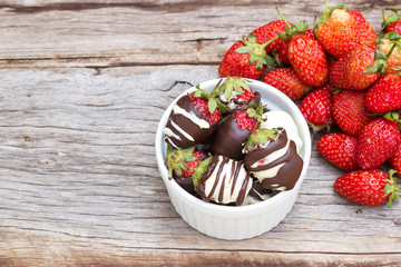 Strawberries dipped wiht chocolate. In white bowl. On wood background. Sweet dessert.