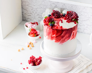 A beautiful chocolate cake with cheese cream, meringues, chocolate and fresh pomegranate on a light vintage background. Provence style. The original idea for a wedding cake or birthday cake.