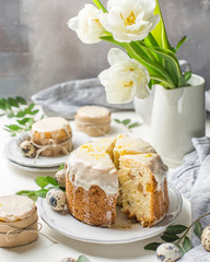 Traditional Easter cake on a light wooden background. Decorated with flowers. Next to a small cake, quail eggs and flowers. Cut a piece of cake. Easter. Celebration. Spring. Rustic style