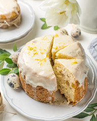 Traditional Easter cake on a light wooden background. Decorated with flowers. Next to a small cake, quail eggs and flowers. Cut a piece of cake. Easter. Celebration. Spring. Rustic style