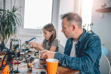 Father and daughter working on electronics components