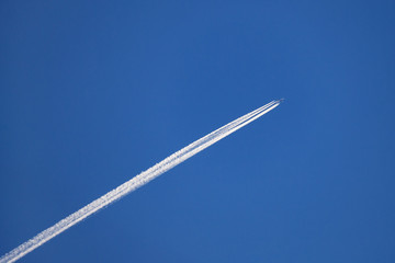 Airplane with an condensation trace behind in the deep blue sky