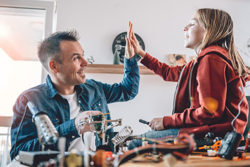 Father and daughter working on electronics components and cheering