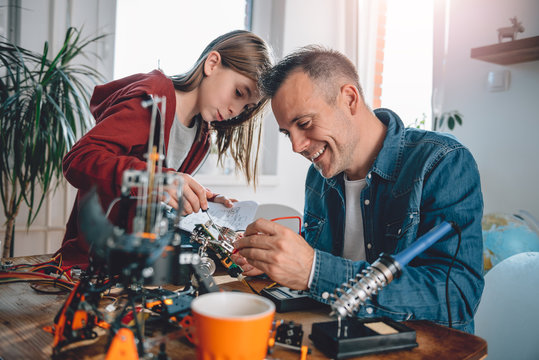 Father and daughter building robot and having fun