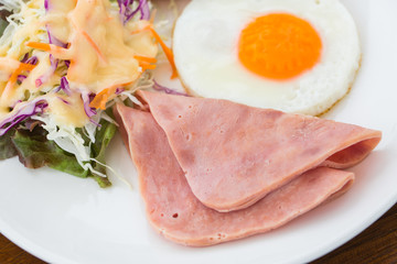 Breakfast with egg, ham, sausage in White dish on wood table
