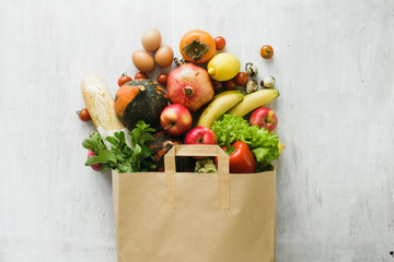 Paper bag of different health food on white wooden background