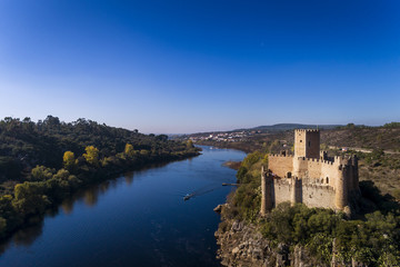 Fototapeta na wymiar Aerial view of the Armourol Castle with a boat passing in the Tagus River in Portugal; Concept for travel in Portugal