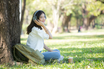 Asian Woman using Headset with attractive smiling at garden. People lifestyle concept.