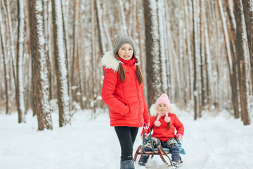 Fototapeta na wymiar Two small smiling girls ride a sled on a winter vacation.