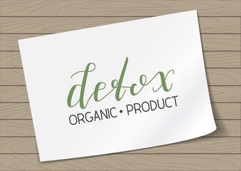 Badge Detox Organic Product with Hand Drawn Lettering on A4 Sheet Paper on Wooden Background. Green Emblem Vector Illustration.