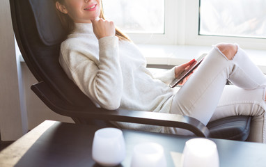 Woman sitting by the window with an e-book