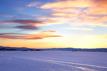 Baikal Lake. Ice winter road near Olkhon Island at sunset. Winter travel on the frozen lake