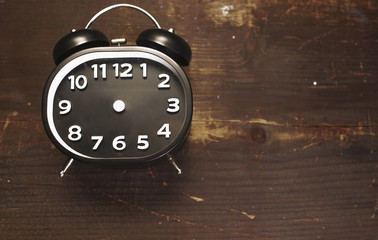 a black and white vintage alarm clock laying on a wooden background