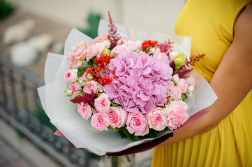 woman holds bouquet of roses, astilba, carnations and hydrangea