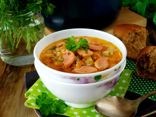 Soup with sausages in a white bowl on a green polka dots cloth
