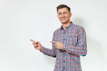 Handsome cheerful positive satisfied caucasian smiling fun young happy man 25-30 years in blue plaid shirt pointing index fingers aside on white background isolated, copy space for advertisement.