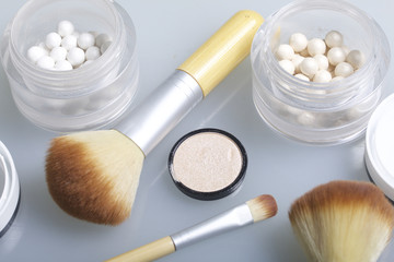 Golden and pearl highlighter in the form of balls in an open jar. Close to the brush for applying...