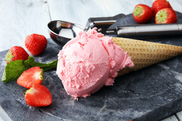 Delicious strawberry ice cream in waffle with fresh strawberries on wooden background