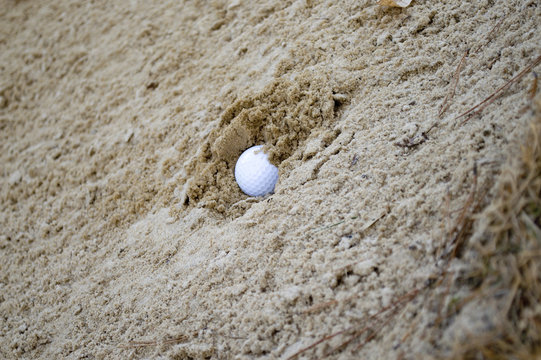 Golf ball buried in sand trap