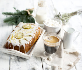a glass with coffee and small marshmallow, a cupcake and a branch of a Christmas tree, on a white wooden background