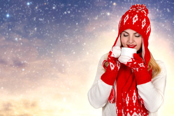 Beautiful young woman in a beautiful knitted hat, mitten and scarf drinks a cup of tea.Fashionable knitted clothes.Merry Christmas and Happy Holidays!