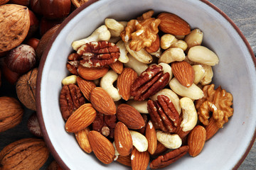 bowl with mixed nuts on wooden background. Healthy food and snack. Walnut, pecan, almonds, hazelnuts and cashews.