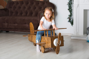 Little cute girl on a wooden toy plane
