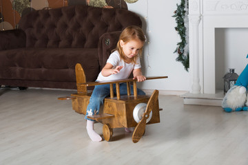 Little cute girl on a wooden toy plane