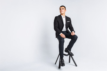 Portrait of the beautiful posing in a Studio, White background, Stylish business man, Stylish man sitting on a designer chair