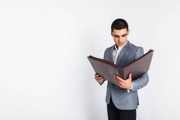 Handsome man with folder man reading a menu, a stylish business guy in suit in Studio on white background