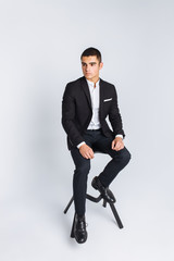 Portrait of the beautiful posing in a Studio, White background, Stylish business man, Stylish man sitting on a designer chair