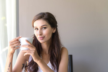 Woman having coffee and smile. Beautiful white woman having her morning coffee and smile looking very happy.