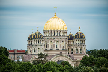 Obraz premium Orthodox Cathedral golden dome above Riga city trees.