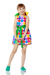 A little girl in a dress with a pattern from multi-colored circl