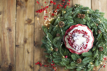 cake with red berries, glass of wine near the Christmas tree on a wooden background