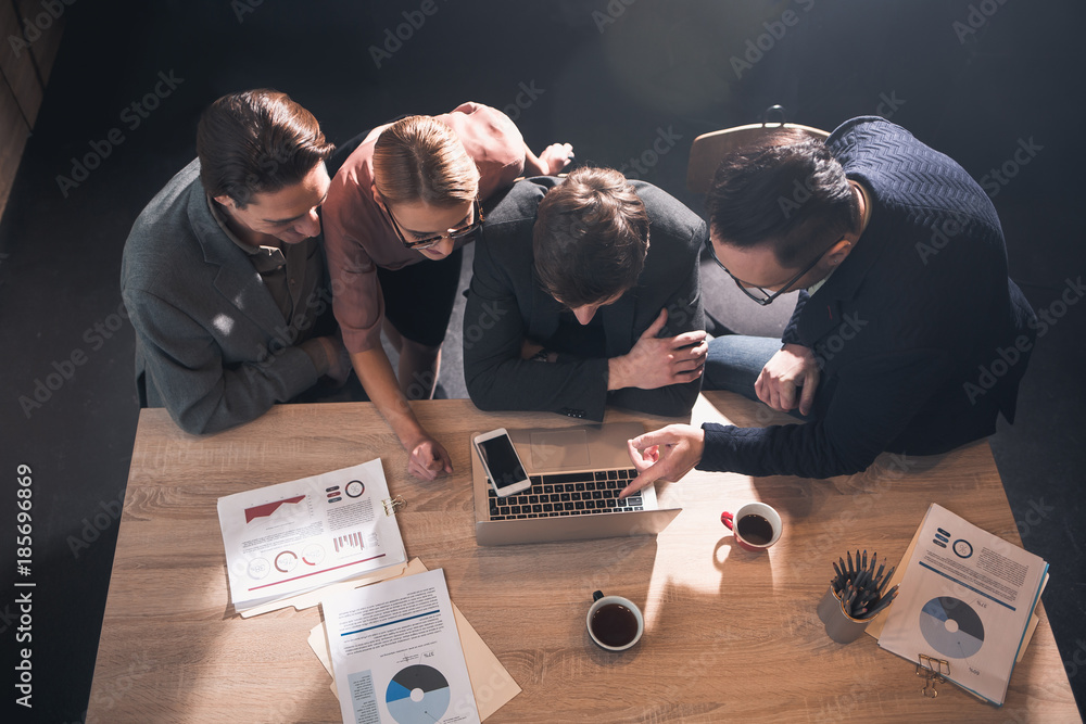 Aufkleber top view smiling lady and beaming men telling with each other while looking at laptop in room. profe