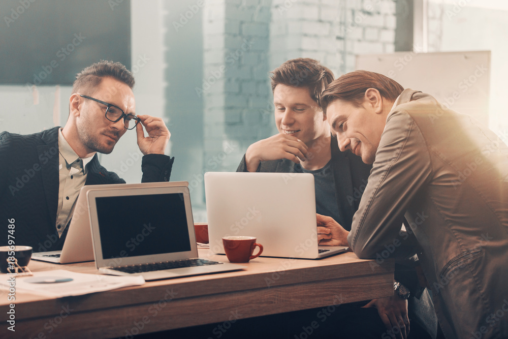 Wall mural outgoing partners looking at display of laptop while sitting at table in office. profession concept