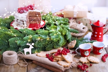 two small cups of coffee and a coffee pot, a cake with berries and cookies, gifts, near a Christmas tree on a village table near the window