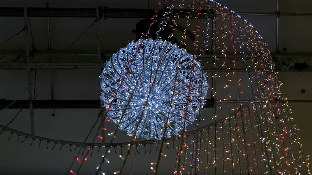 Industrial climber mounts Christmas decorations in the unsupported space in the shopping center