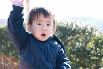 手をあげて返事をする1歳児