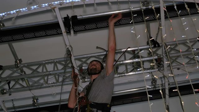 Industrial climber mounts Christmas decorations in the unsupported space in the shopping center