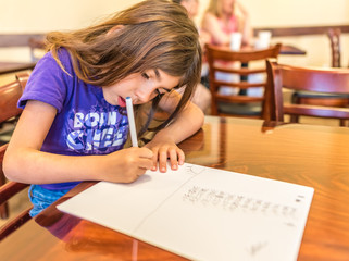 Vacationing caucasian girl works on homework in the hotel breakfast area in California