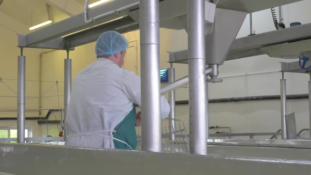 Cheese factory employee replaces machine part on milk vat