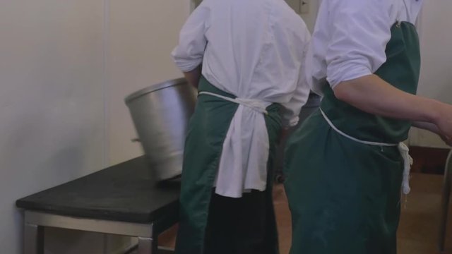 Two factory employees empty out cheese vats once the cheese has settled