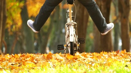 Happy  man with the raised legs on Bicycle in autumn park  - Powered by Adobe