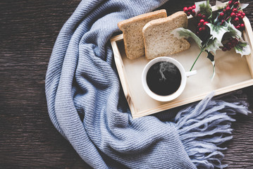 Cup of coffee on rustic wooden serving tray in the cozy winter with blanket. Knitting warm wooden sweater in the winter weekend, top view. Lifestyle Concept.