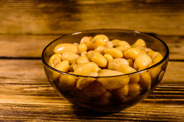 White marinated haricot beans in glass bowl on a wooden table