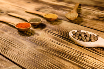 Spoons with the different spices on wooden table
