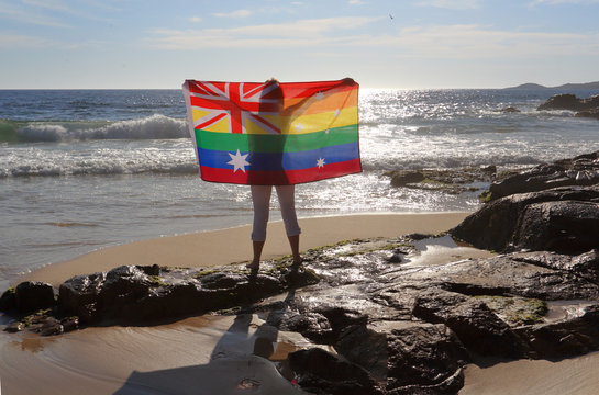 Female holding an Australian flag in rainbow colours